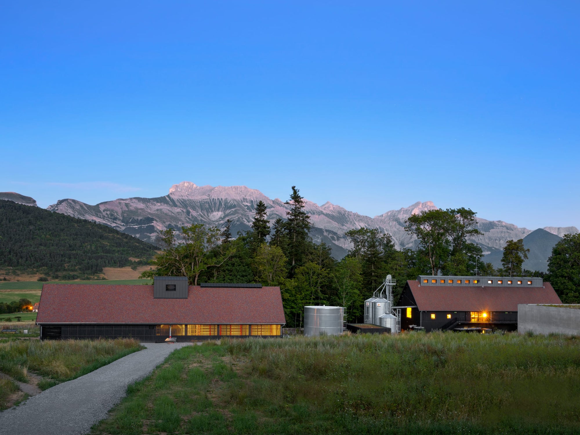 Distillerie, malterie et chai de vieillissement des Hautes Glaces, sur fond de montagnes alpines : la chaine de l'Obiou.